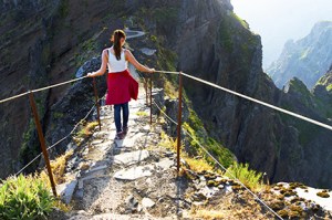 Young girl on the winding mountain trekking path at Pico do Aree
