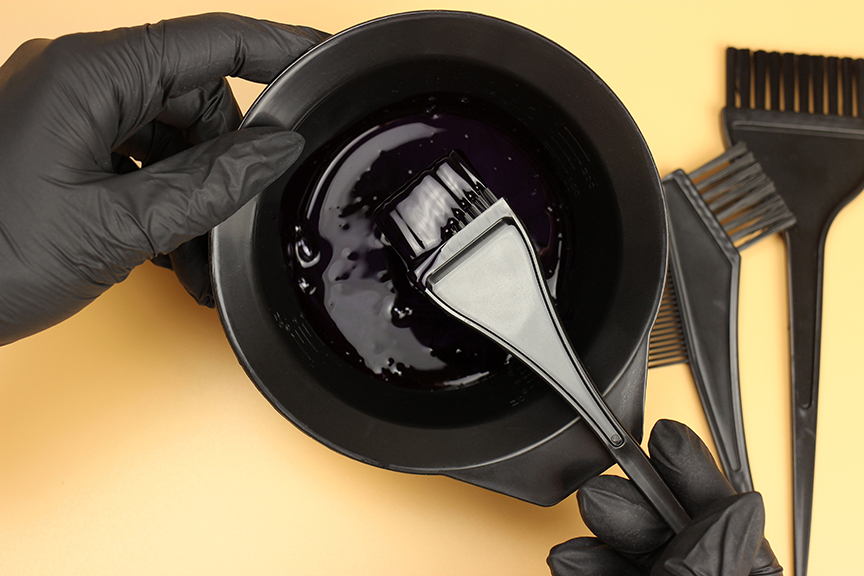 Girl in black gloves mixes hair dye in a bowl