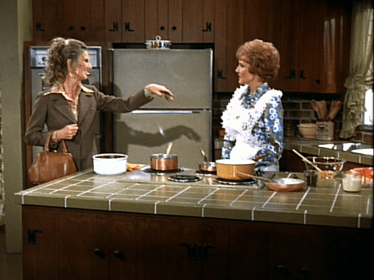 Phyllis (Cloris Leachman) sprays Sue Ann (Betty White) with chocolate, all over Sue Ann's white apron.