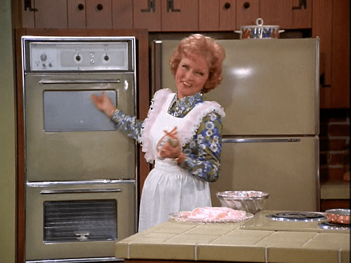 Sue Ann (Betty White) checks the oven to see why her dessert failed.
